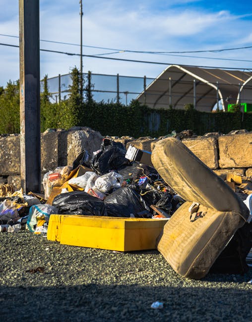 A pile of construction debris and rubble, including broken bricks, pieces of concrete, and fragments of wood, is scattered across a partially collapsed outdoor area adjacent to a multi-storey building